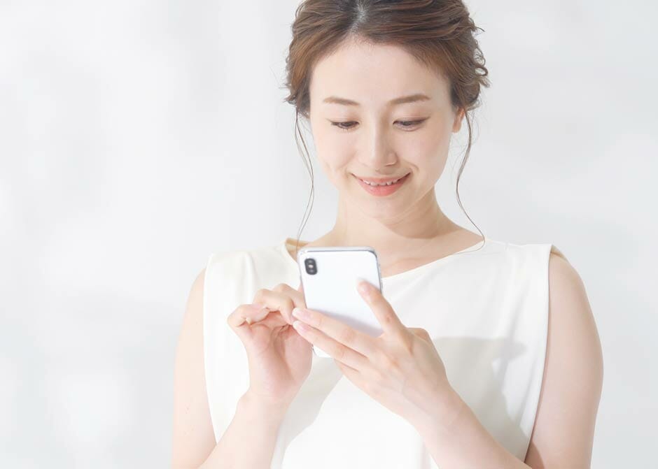 スマートフォンに届いた結婚式のWEB招待状を見ている女性