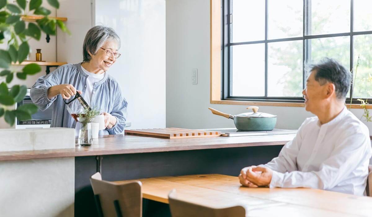 キッチンでコーヒーを淹れながら会話しているシニア夫婦